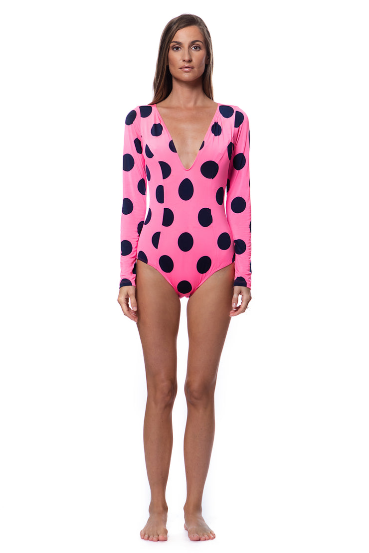 Bella Paradise pink polka dot long sleeve one piece swimsuit with deep V neckline on model