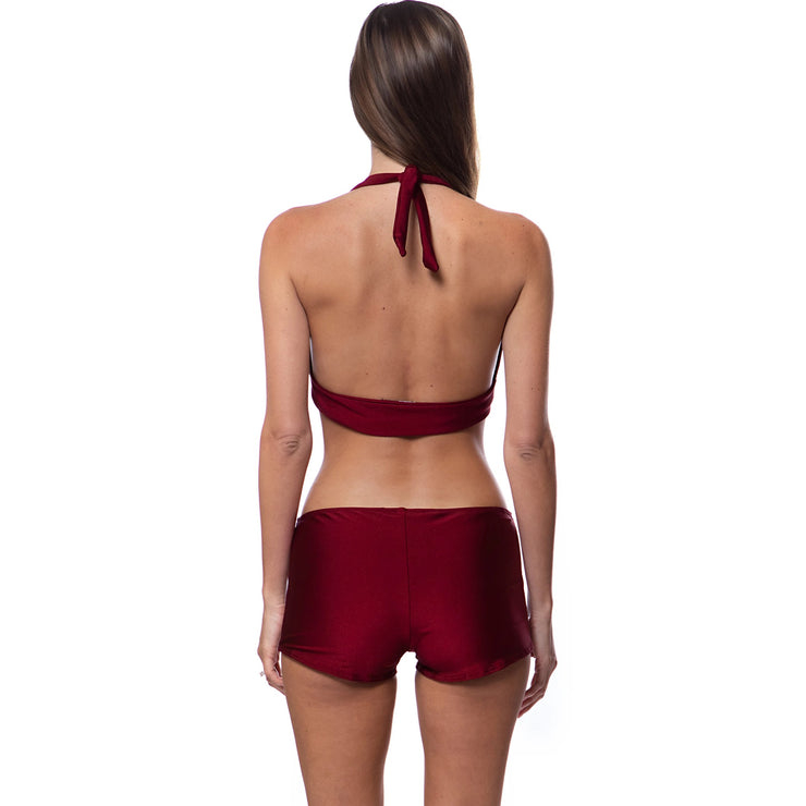 Woman wearing designer resort wear swim bottoms in deep red from Bella Paradise shown from back