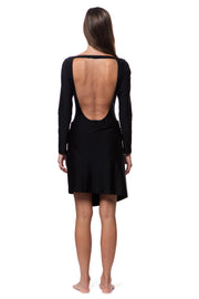 Back view of woman wearing a black luxury resort skirt with long sleeve swimsuit with open back