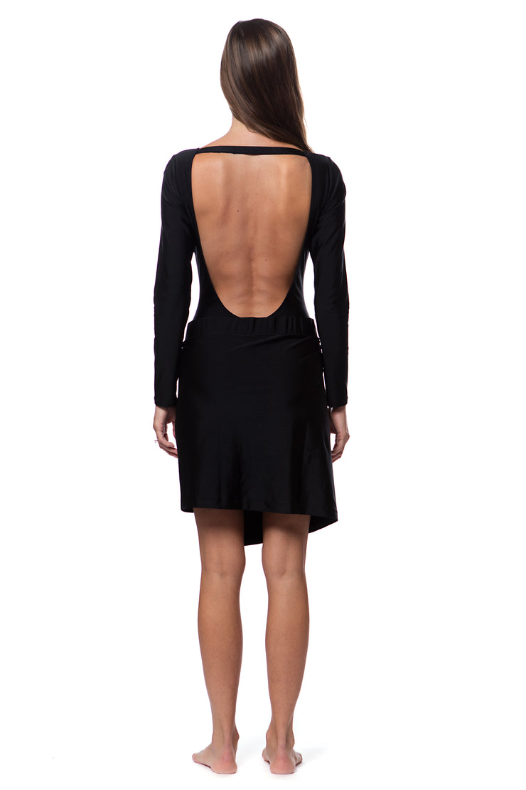 Back view of woman wearing a black luxury resort skirt with long sleeve swimsuit with open back