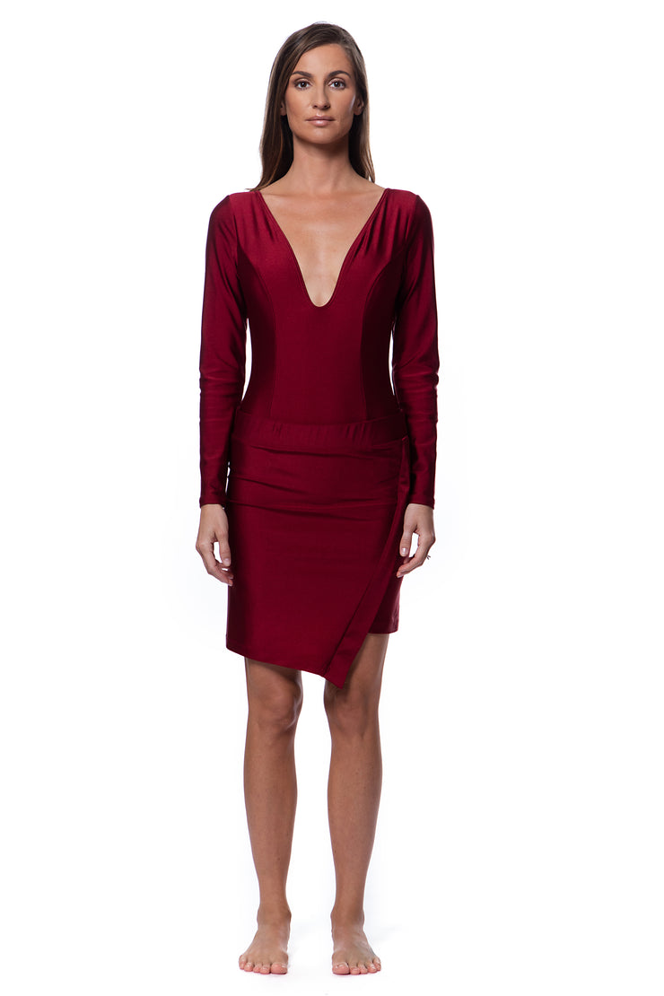 Woman wearing a deep red luxury resort skirt with long sleeve swimsuit with a plunging neckline by Bella Paradise
