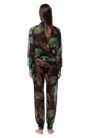 Back view of woman wearing Bella Paradise tropical print mesh bomber with matching pants in dark green leaf pattern