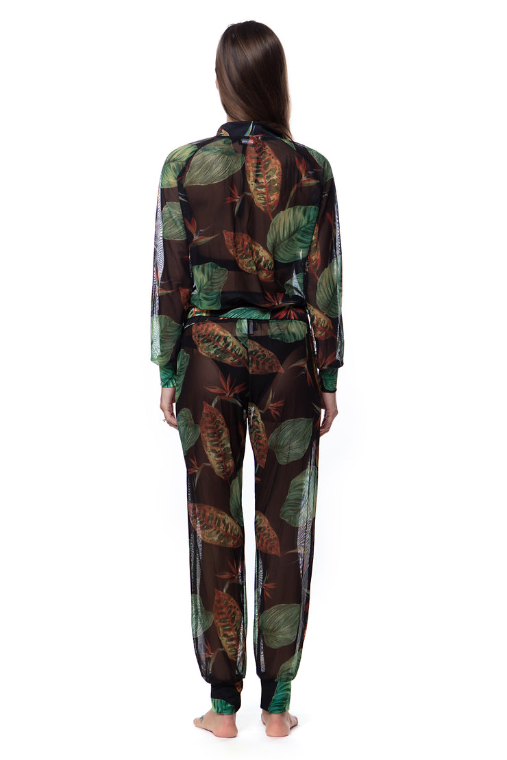 Back view of woman wearing Bella Paradise tropical print mesh bomber with matching pants in dark green leaf pattern