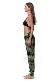 Side view of woman wearing Bella Paradise versatile mesh cover up pants in green leaf print with black bikini top