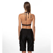 Bella Paradise women's board shorts in black shown from the back on a model with a halter bikini top