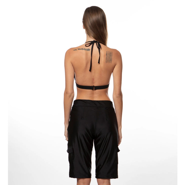 Bella Paradise women's board shorts in black shown from the back on a model with a halter bikini top
